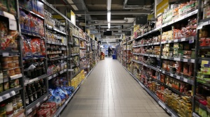 allée de supermarché avec rayonnages et clients en arrière-plan, illustrant les prix psychologiques
