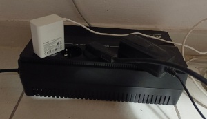 Onduleur APC Easy UPS en service Onduleur APC Easy UPS branché dans un espace restreint avec câbles visibles